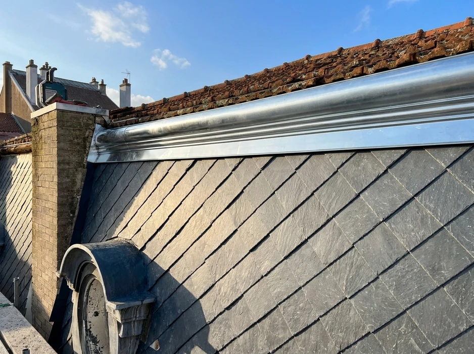 Toiture en ardoise naturelle grise avec un solinage en plomb laminé brillant formant un joint à bourrelet