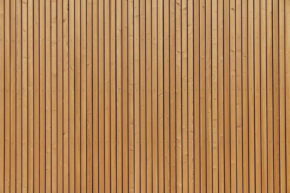 Façade extérieure en bardage bois vertical, lames de bois naturel disposées parallèlement avec joints creux réguliers