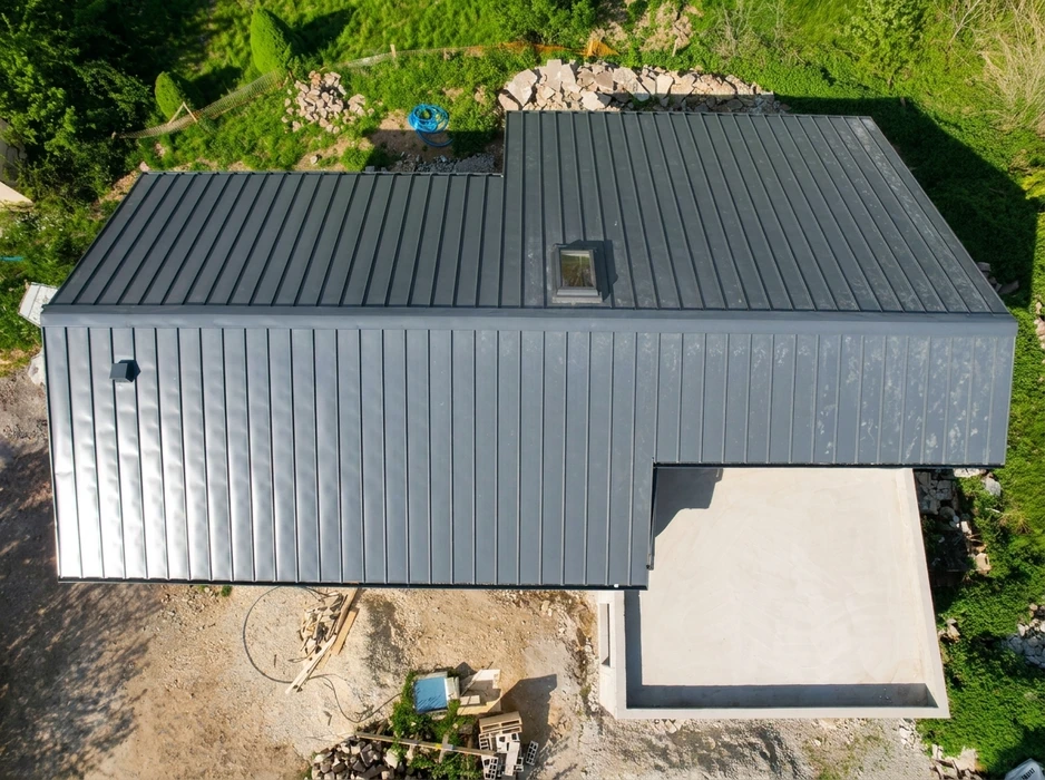 Vue aérienne d'une maison moderne en construction, toiture et bardage en zinc anthracite à joints debout (standing seam)