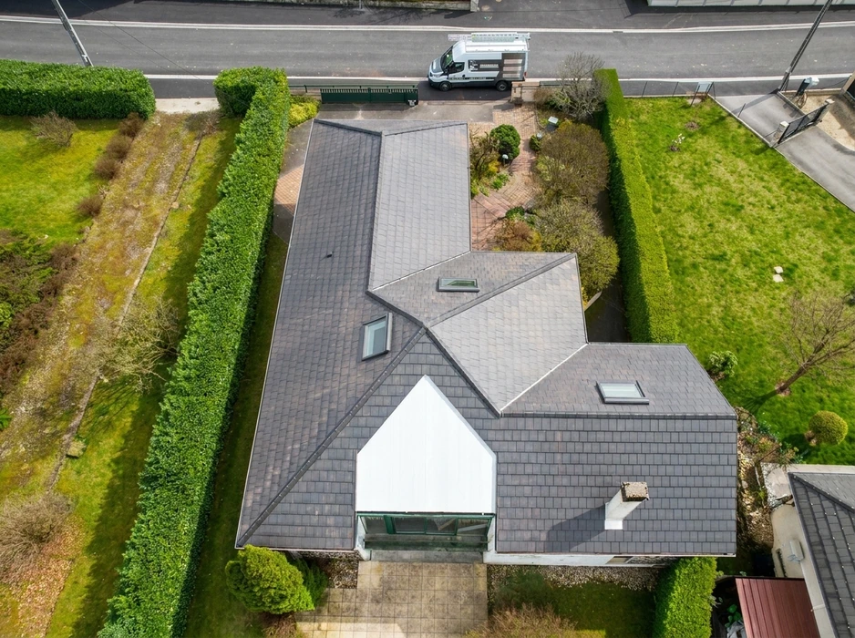 Vue aérienne d'une maison individuelle avec toiture en ardoises naturelles grises, structure complexe à pans multiples