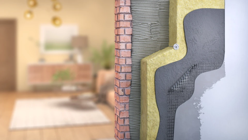 Ouvrier appliquant un enduit de façade extérieure à la truelle sur mur en polystyrène expansé près d'une fenêtre avec cadre orange