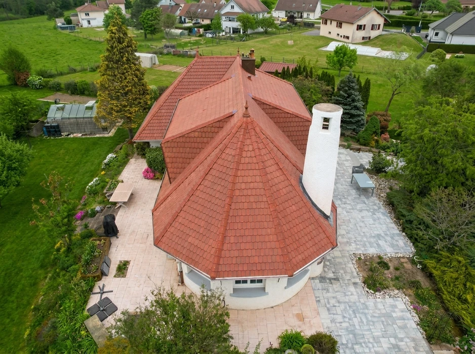 Chantier de construction résidentielle en extérieur avec ouvrier couvreur installant des tuiles grises sur charpente en bois